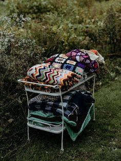 a pile of blankets sitting on top of a metal rack in the middle of a field