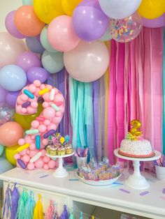 a table topped with lots of balloons and cake