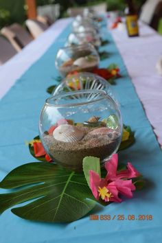 there are many fish bowls on the table with flowers and rocks in them, along with other decorations