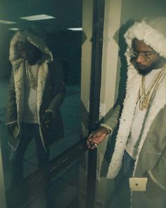 a man in a fur coat is looking at his reflection in the mirror while wearing a hoodie