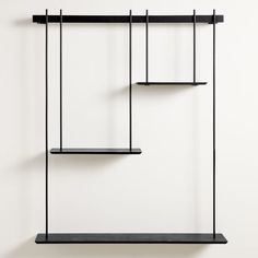 three black shelves on the wall with one hanging from it's side and two empty shelves above them