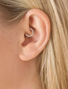 a woman's ear with a single blue stone in the middle