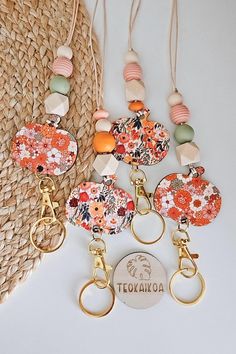 several keychains with different designs and colors hanging on a rope next to a straw bag