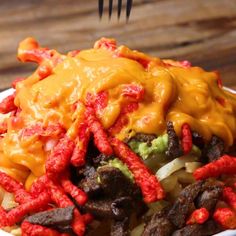 a white bowl filled with meat and vegetables covered in cheese on top of a wooden table