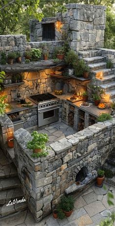 an outdoor kitchen with stone walls and steps leading up to the top floor, surrounded by potted plants