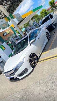 two white cars parked in front of a gas station