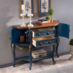 a blue table with two pictures on the wall above it and a lamp next to it