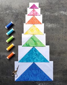 several different colored pieces of paper next to scissors and thread