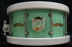 a close up of a green and white drum with mustaches on the front side