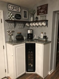 a kitchen with white cabinets and shelves filled with wine glasses on top of the counter