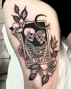 a couple of skulls sitting on top of each other with flowers and leaves around them