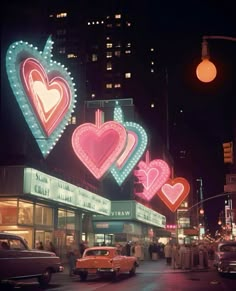 an old photo of neon signs and cars on a city street