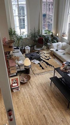 a living room filled with lots of furniture next to tall windows on top of a hard wood floor