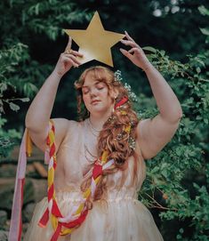 a woman in a dress holding a star above her head