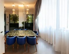 a dining room table with blue chairs next to a window