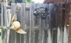 a wooden fence with two metal fish heads on it's sides and one is hanging from the side