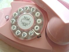 an old pink rotary telephone with white buttons