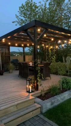 a gazebo with string lights on it in the middle of a garden area at dusk