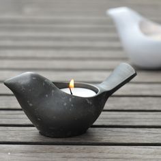 a candle that is sitting on top of a wooden table next to a tea light holder