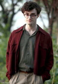 a young man wearing glasses standing in front of trees