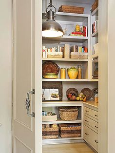 an open pantry with lots of food and baskets on the bottom shelf in front of it