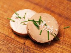 two pieces of bread sitting on top of a wooden table covered in sprigs