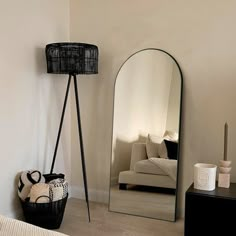 a room with a mirror, lamp and basket on the floor in front of it