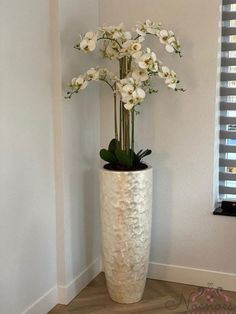 a tall white vase with flowers in it