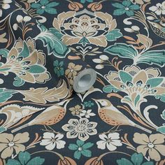 a blue and brown flowered fabric with a white vase in the center on it