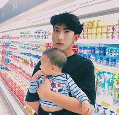 a man holding a baby in his arms while standing next to a grocery store shelf