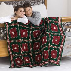 a man and woman laying in bed under a crocheted blanket with snowflakes on it