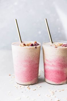 two glasses filled with food sitting on top of a white table next to each other