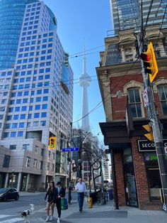 people are walking down the street in front of some tall buildings and a yellow traffic light