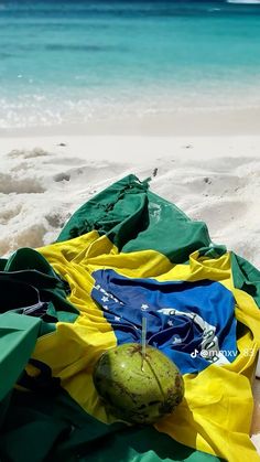 a green and yellow towel sitting on top of a sandy beach next to the ocean