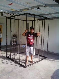 a man standing in front of a metal cage with his arms up and hands behind the bars