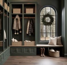 an entryway with green painted cabinets and wooden flooring is decorated with wreaths