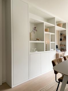 a dining room table and chairs in front of white bookcases with open shelves