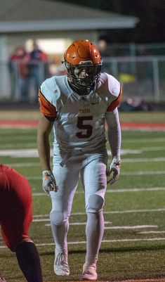 a football player is getting ready to kick the ball while standing on the sideline