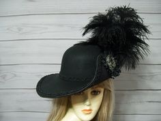 "Black Cavalier woolen hat with black braided trim, black ostrich plumes, black cocarde with a dark sparkly jewel center. This hat is 22.5\" for the inside circumference but does have a built-in hat sizer. I'm sorry, I cannot make the inside circumference bigger. If you're looking for a different color scheme, please don't hesitate to reach out to me. I'm always happy to help. I ship Priority mail. I ship many times a week. If you need your item quicker let me know your zip code and I can figure Cavalier Hat, Musketeer Hat, Fair Costume, Black Pirate, Foam Wigs, Pirate Outfit, Ren Fair, Pirate Hat, Woolen Hat