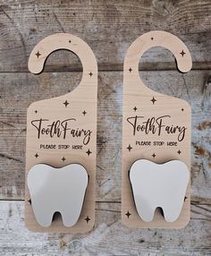 two tooth shaped magnets are on top of a wooden board, with the words tooth fairy printed on them