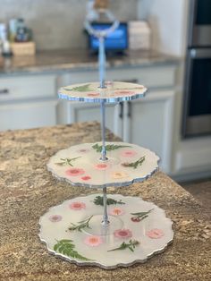 three tiered trays with flowers on them sitting on a countertop in a kitchen