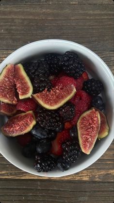 a white bowl filled with fruit on top of a wooden table