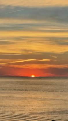 the sun is setting over the ocean with boats in the distance