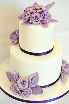 a three layer white cake with purple flowers on top