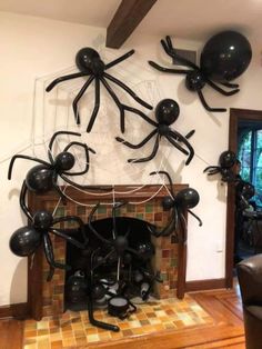 some balloons are hanging from the ceiling in front of a fire place with spider decorations on it