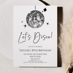 a party card with a disco ball and stars on it, next to a feather