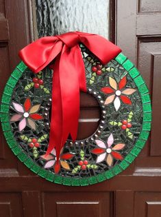 a stained glass wreath with a red bow hanging on the front door, decorated with flowers and leaves