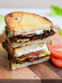 a grilled sandwich with lettuce, tomato and cheese on a cutting board