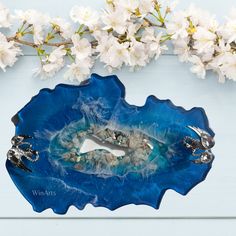 a blue bowl with white flowers on the side and two rings in the middle sitting next to it