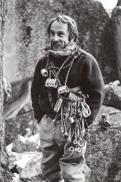 a man standing next to a tree in front of a stone wall with chains on it